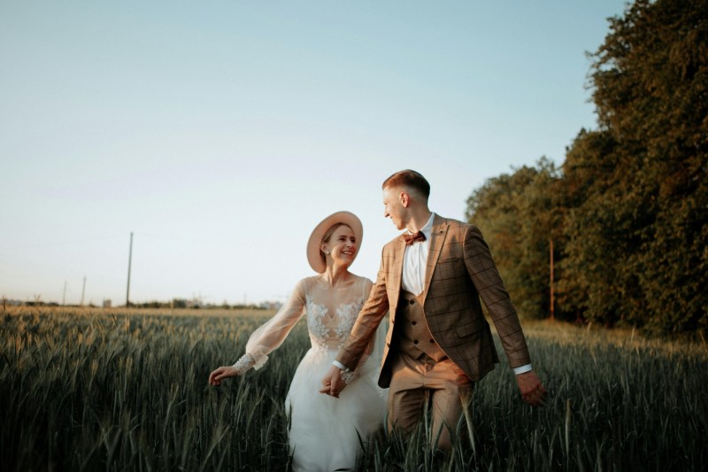 Couple in a field where he is wearing a brown suit
